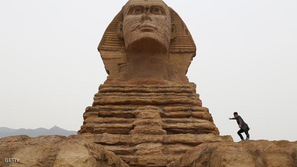 A man poses for photographs on a full-scale replica of the Sphinx on the outskirts of Shijiazhuang