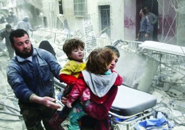 A boy carries two children as he evacuates them from a site hit by what activists said was a barrel bomb dropped by forces loyal to Syria's President Bashar al-Assad in Aleppo's al-Fardous district